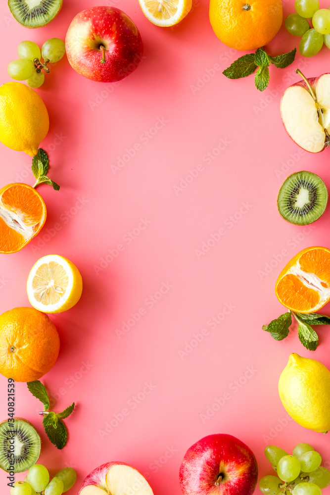 Oranges, lemon, apple, kiwi and grape - healthy food concept with fruits - on pink background top-down frame copy space Oranges, lemon, apple, kiwi and grape - healthy food concept with fruits - on pink background top-down frame copy space