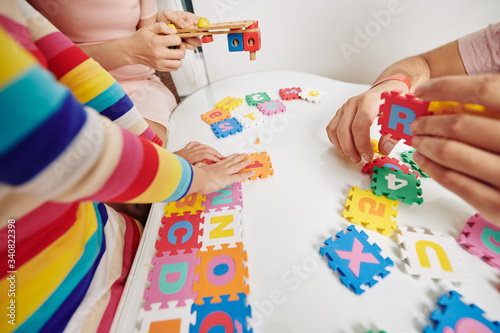 Parents and daughter playing with letter puzzle when staying at home during quarantine