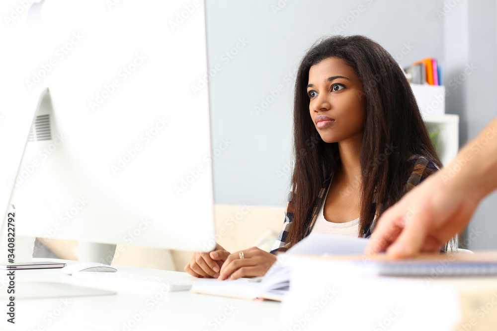 Black smiling woman sitting at workplace working with desktop pc studying or doing school homework concept Black smiling woman sitting at workplace working with desktop pc studying or doing school homework concept