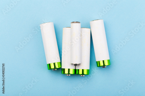 many new and used batteries of different shapes, AA, round batteries on a blue background.