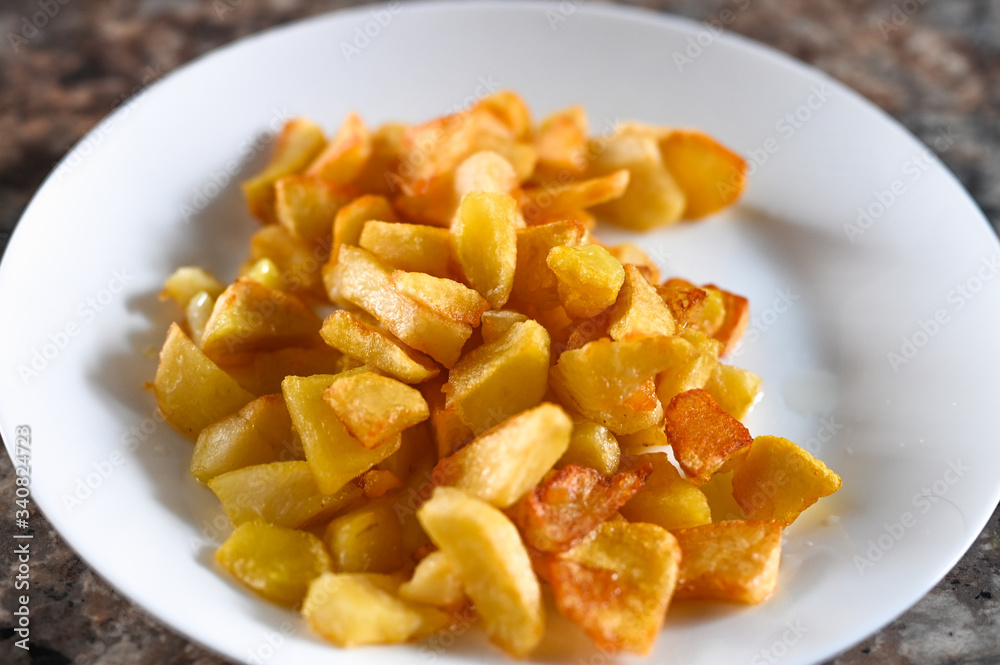fried golden potatoes on a white plate. Fried potato wedges fried golden potatoes on a white plate. Fried potato wedges