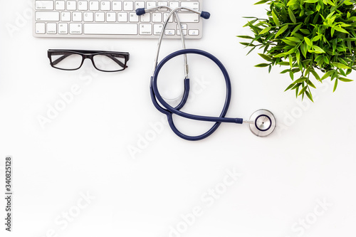 Stethoscope on doctor office desk. White background from above copy space