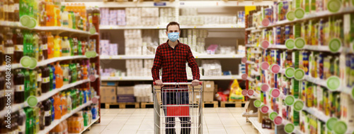 Man in protective mask shopping in supermarket pushing trolley during epidemic photo