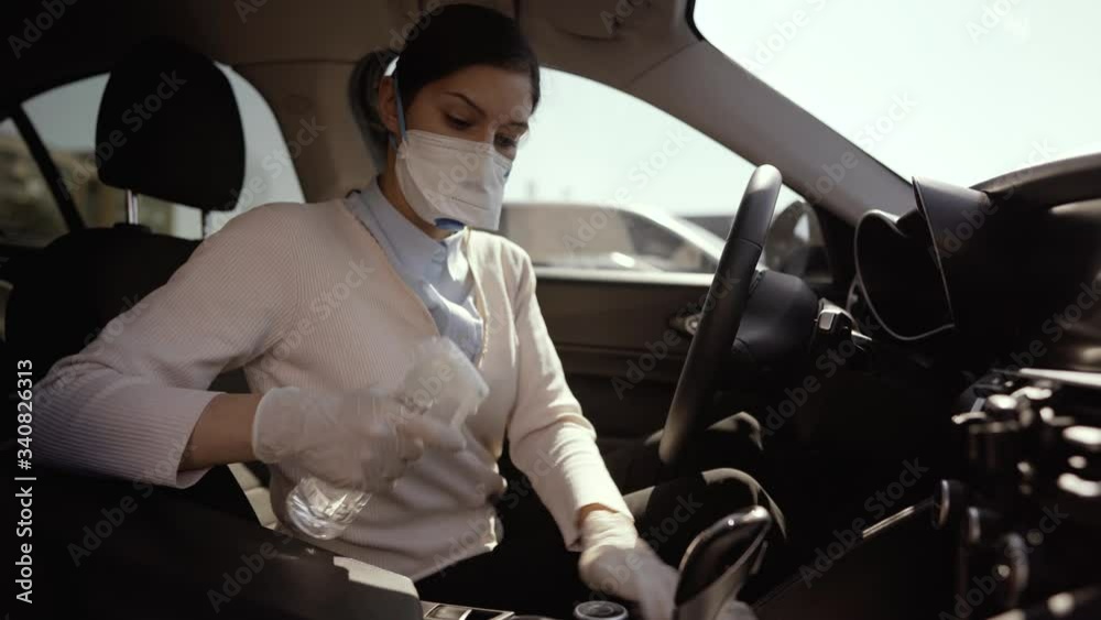 Car owner disinfecting vehicle with alcohol based sanitizing solution spray.Touched surfaces sanitation.Coronavirus COVID-19 spread prevention.Cross-contamination.Steering wheel disinfection