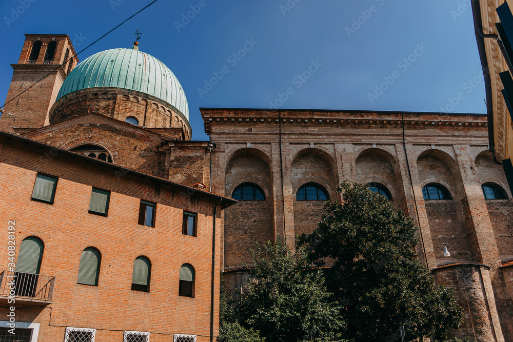 The building is made of red stone with a large green dome against the blue sky on a Sunny day | VENICE, ITALY - 16 SEPTEMBER 2018. 