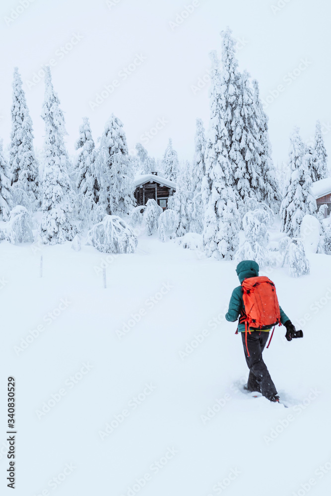 Female photographer walking to a cabin in the snowy woods