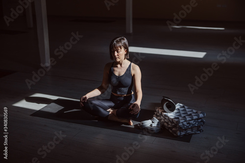 Young calm yogi woman in lotus yoga pose. Yoga studio interior.