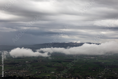 View from above of Umbria valley, with clouds above and below the viewer. © Massimo