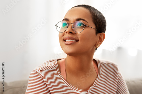 people, vision and leisure concept - portrait of happy smiling african american woman in glasses at home