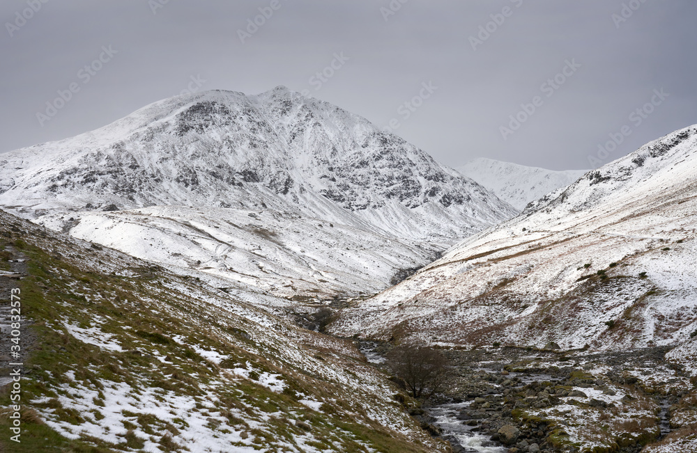 Snow and ice covered mountain of Catstye Cam with Lower Man in the distance and Glenridding Beck in the foreground. Lake District. UK.