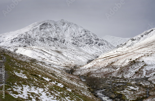 Snow and ice covered mountain of Catstye Cam with Lower Man in the distance and Glenridding Beck in the foreground. Lake District. UK.