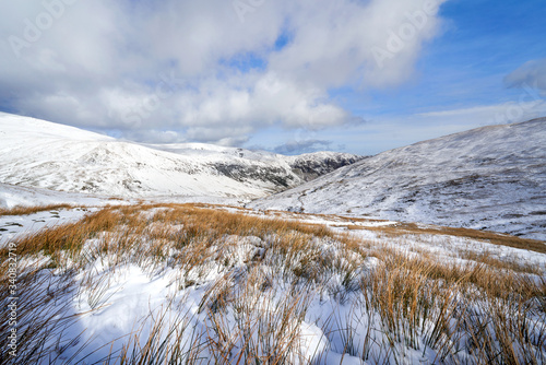 A snow covered Glenridding Beck below Catstye Cam with Glenridding Screes in the distance on a sunny winters day in the Lake District, UK. photo