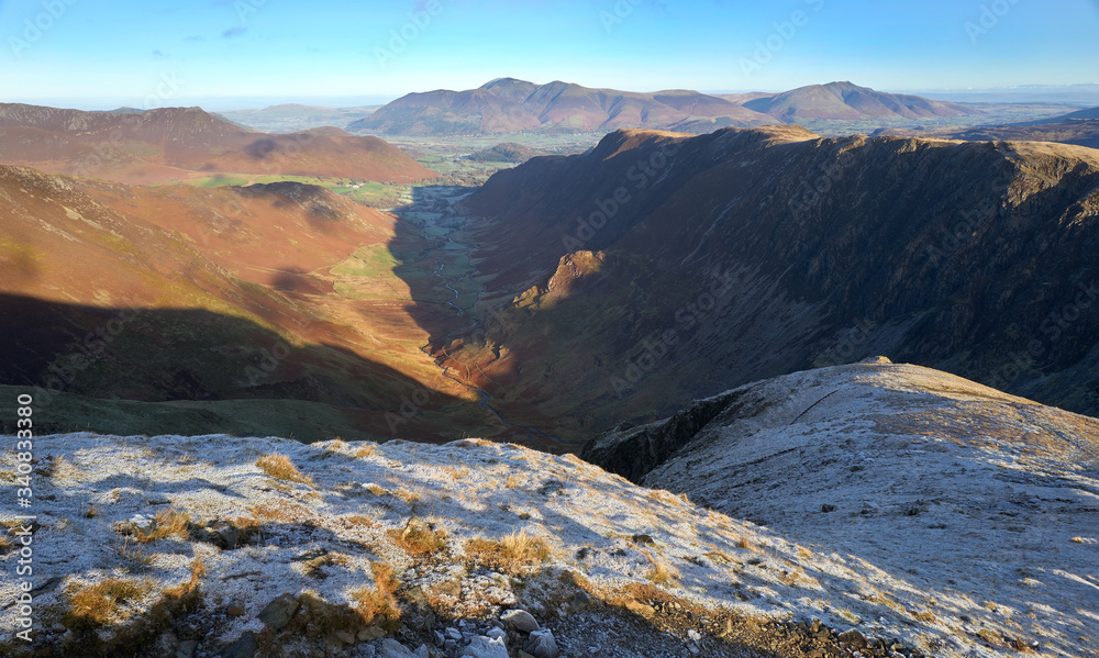 The frozen ground at sunrise on top of Dale Head with the valley of Newlands Beck below surrounded by High Crags, Maiden Moor & High Spy, the Derwent Fells in the Lake District in winter, UK.