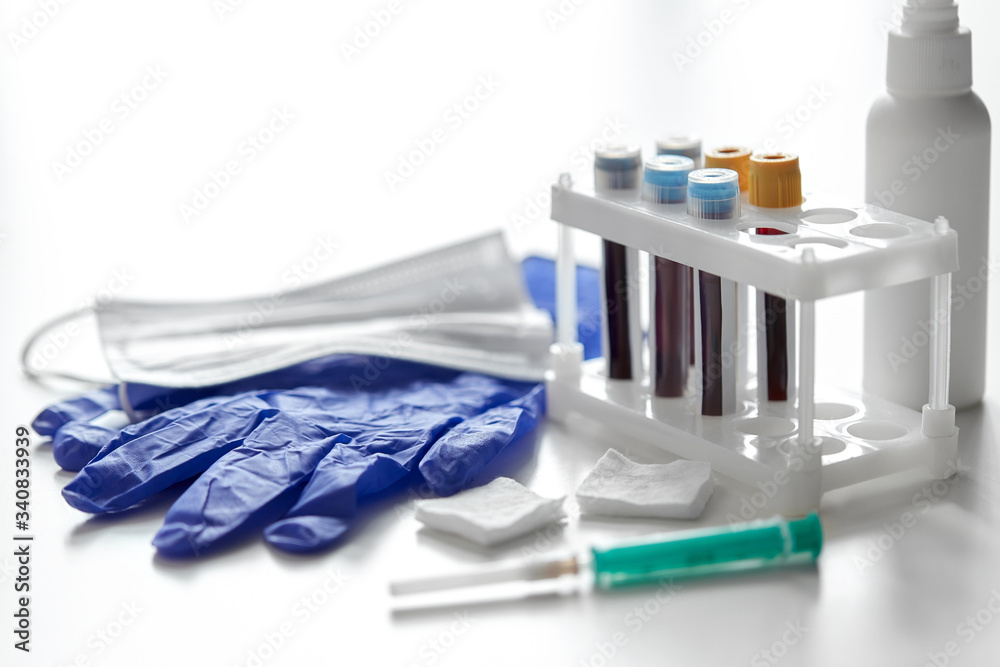 medicine and healthcare concept - close up of beakers with blood test in holder, syringe, mask, wound wipes and gloves at laboratory medicine and healthcare concept - close up of beakers with blood test in holder, syringe, mask, wound wipes and gloves at laboratory