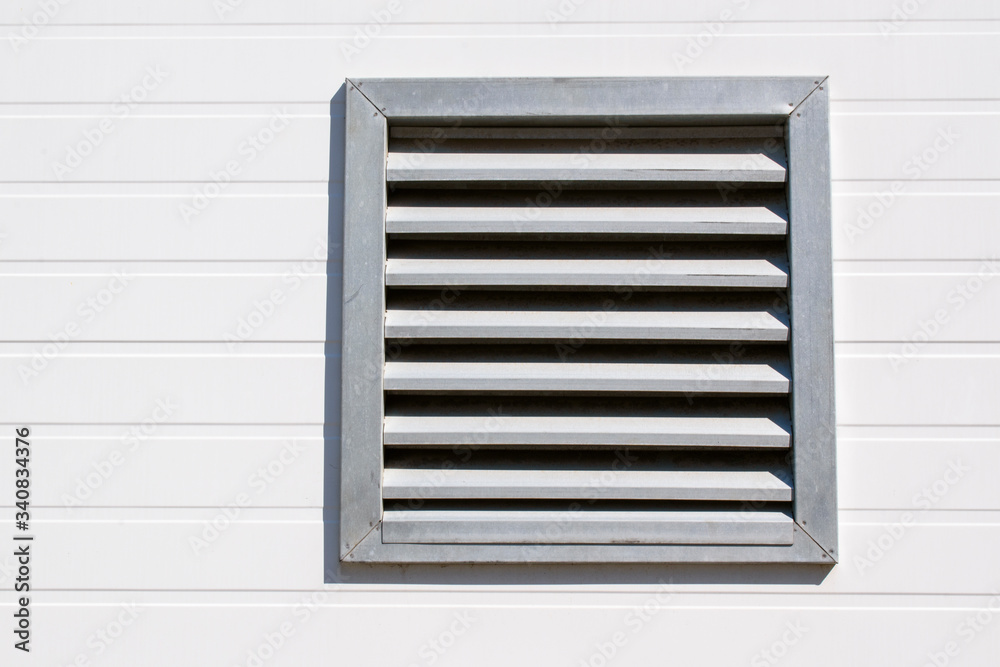 Ventilation hole with stainless steel grill. Wall made of light plastic siding. Horizontal arrangement of the stripes. Ventilation hole with stainless steel grill. Wall made of light plastic siding. Horizontal arrangement of the stripes.