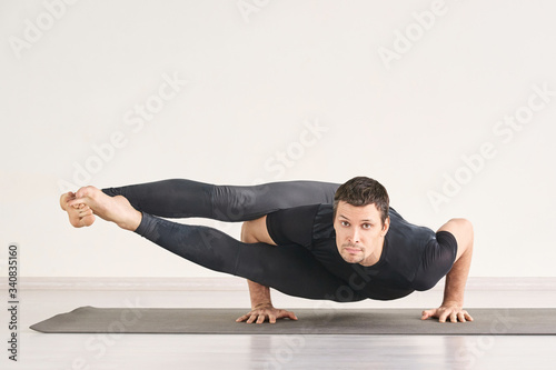 Strong man stand at Astavakrasana. Fitness yoga exercise. Pilates asana. Male gymnast home class. Online isolation personal teacher. Sportsman balance health banner.Horizontal with copyspace. text