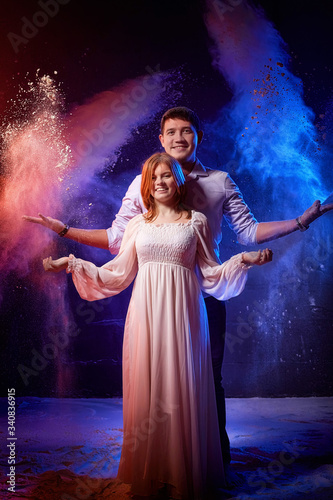 Beautiful young couple during a photo shoot with flour in a dark Studio. A young man and a girl pose together on a black background