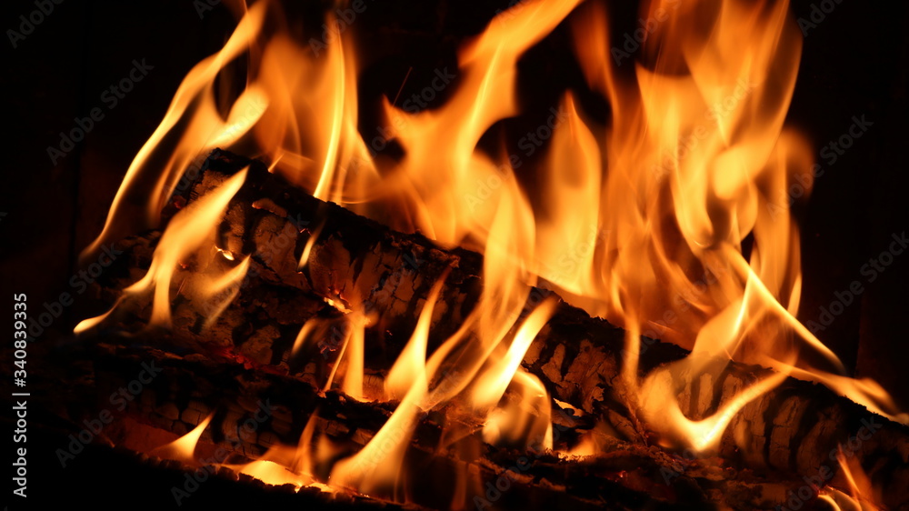bright flames on a burning log in a fireplace in the dark bright flames on a burning log in a fireplace in the dark