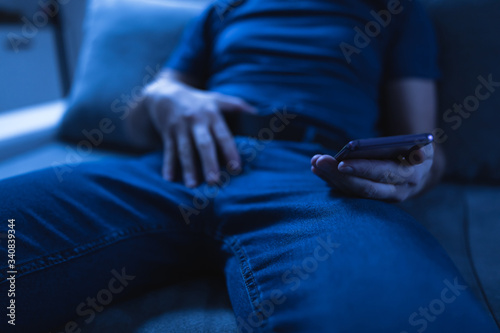 Man holding modern smartphone   cellphone and watching XX videos on a home couch. Taboo still in modern times.
