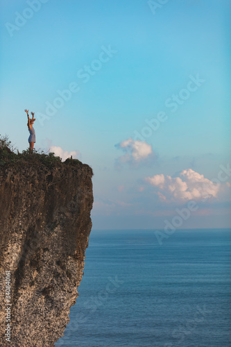 Woman enjoying nice tropical summertime days on the island above tje ocean from a cliff.