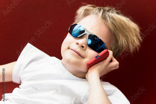 funny boy speaks on smartphone on red background