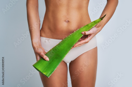 Beautiful adult woman posing naturally with aloe vera leaf