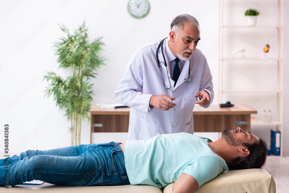 Fototapeta premium Injured young man visiting old doctor