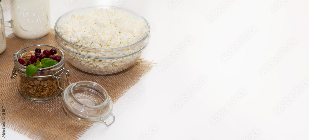 the concept of healthy and proper nutrition. Milk in a jar with a handle, cottage cheese and granola in a jar on a napkin with a mint leaf and cranberries. Banner and copyspace the concept of healthy and proper nutrition. Milk in a jar with a handle, cottage cheese and granola in a jar on a napkin with a mint leaf and cranberries. Banner and copyspace