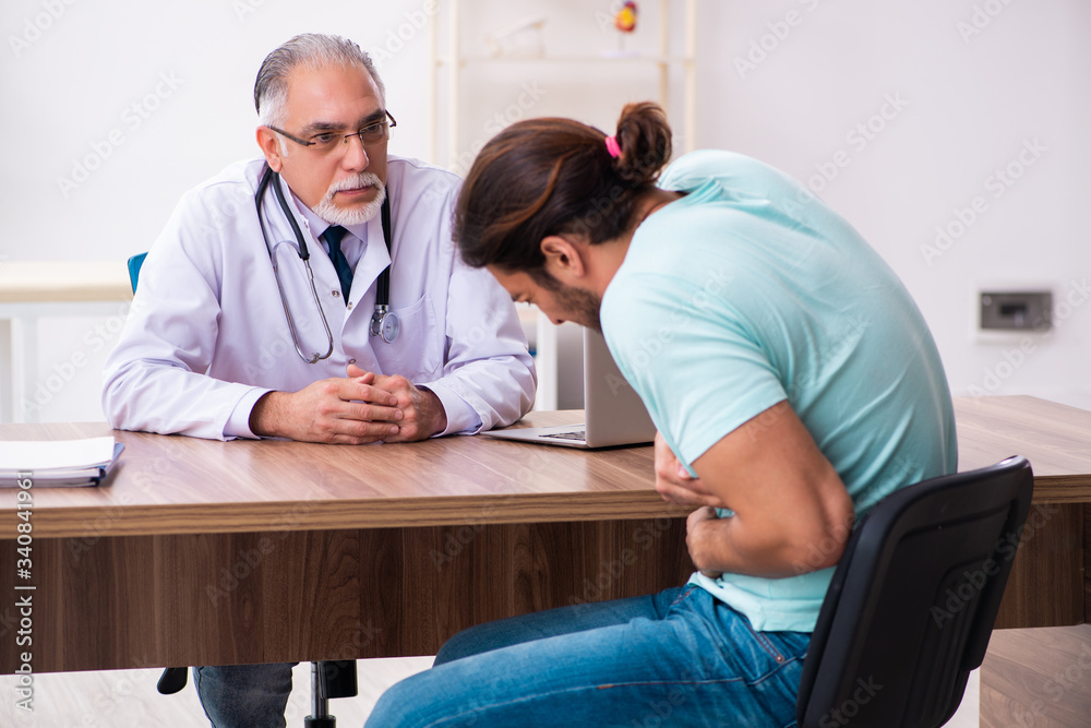 Fototapeta premium Injured young man visiting old doctor