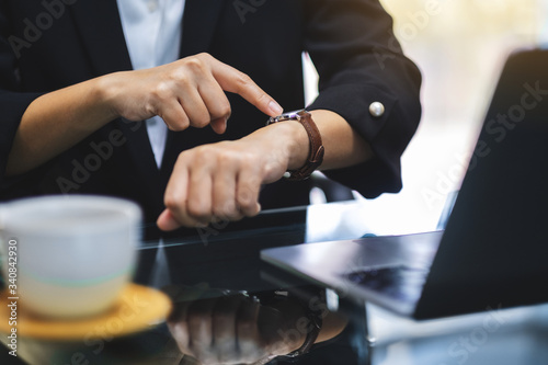 Φωτογραφία A business woman pointing at a wristwatch on her working time while waiting for