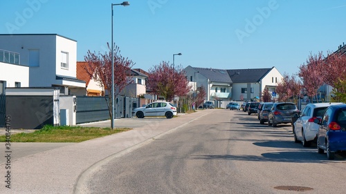Brand new residential houses with car parked on driveway in front. Newly built modern residential park with cars and trees.Blue sky.