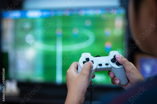 Selective focus gamer hand playing video game at home.A boy enjoy and relax with game online on TV.Stay at home concept.