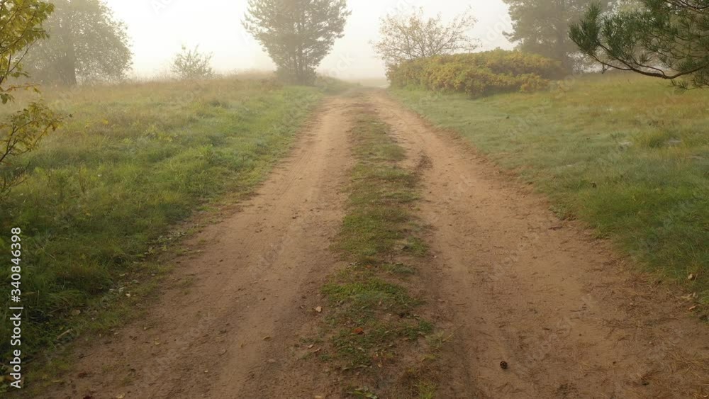 Low angle drone aerial view of countryside sand road in Kaunas county, Lithuania. Autumn season. Foggy morning. Low angle drone aerial view of countryside sand road in Kaunas county, Lithuania. Autumn season. Foggy morning.