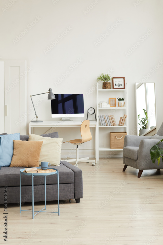 Wide angle background image of cozy apartment interior in minimal Scandinavian design and focus on grey sofa with decor elements, copy space