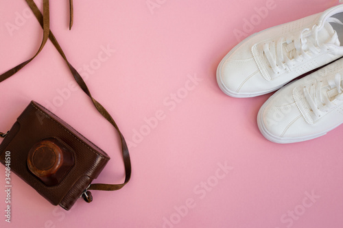 pink background with white shoes and an old camera