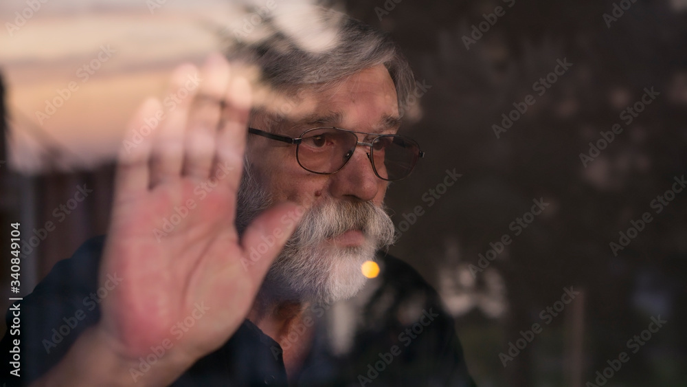 Fototapeta premium Senior man looking outside of the window. Quarantine. Pandemic. Sad.
