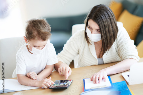 Boy and exhausted mother trying to work at home during coronavirus pandemic