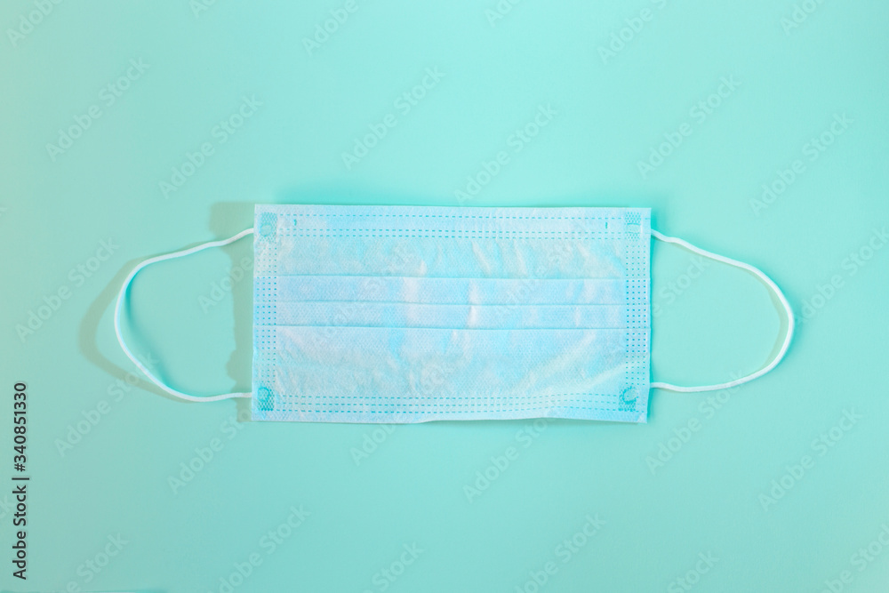 High angle view of a medical face mask on green background.Covid protection. High angle view of a medical face mask on green background.Covid protection.