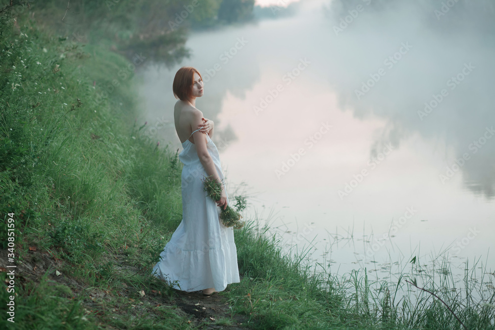 Woman in white dress standing by the lake