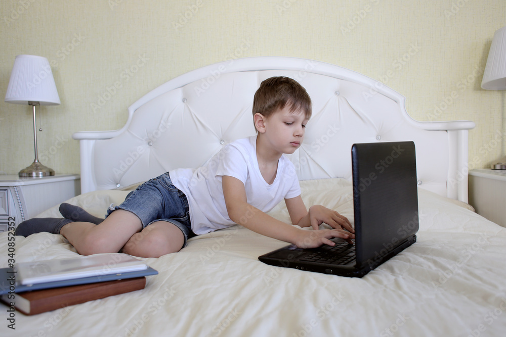 Boy lying on the bed in the bedroom doing homework