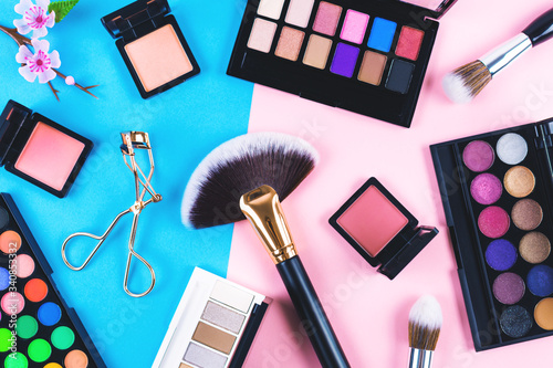 Many makeup products on blue and pink background. Flat lay, top view. 
