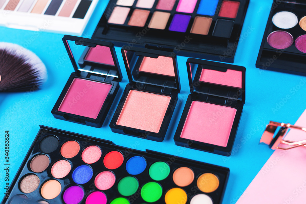 Many makeup products on blue and pink background. Flat lay, top view. Many makeup products on blue and pink background. Flat lay, top view.