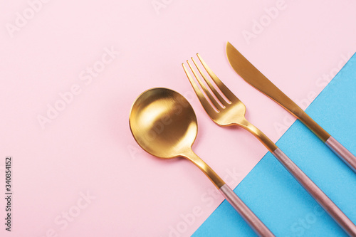 Beautiful cutlery set on pink and blue background. Flat lay, top view. Copy space for your text.