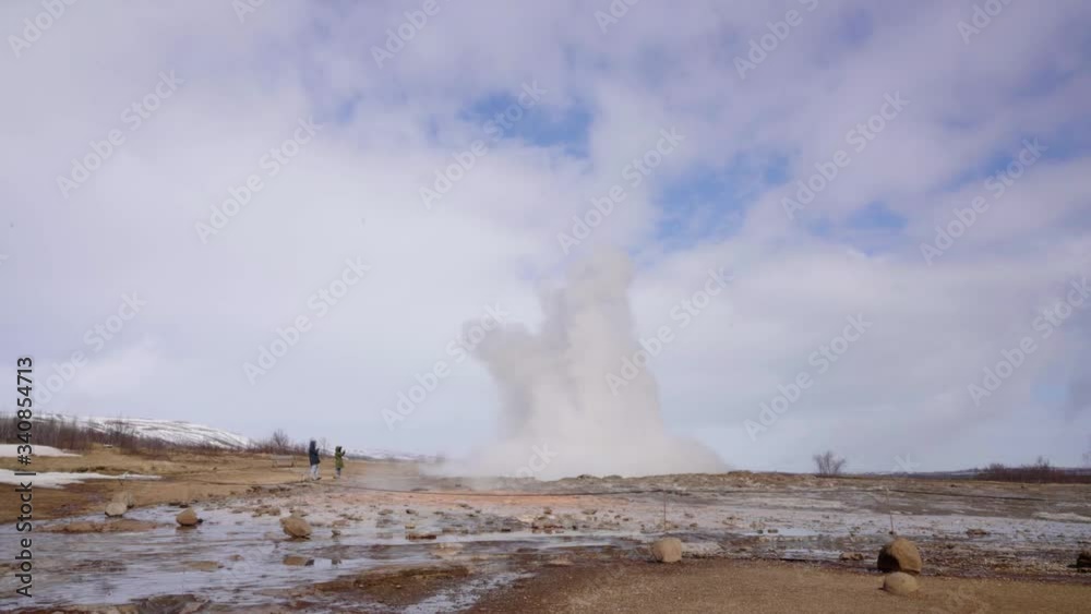 People waiting for the geyser to explode from the ground in Iceland - wide shot People waiting for the geyser to explode from the ground in Iceland - wide shot