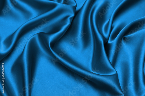 Blue satin, silky fabric, wave, draperies. Beautiful textile backdrop.