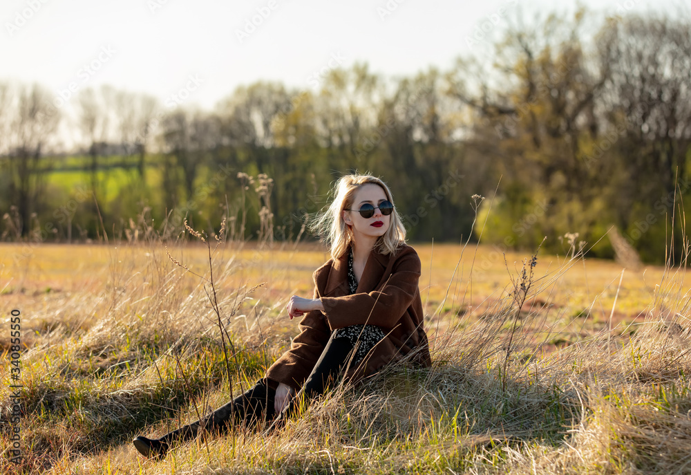 Blonde girl is sitting at countryside in sunset time Blonde girl is sitting at countryside in sunset time