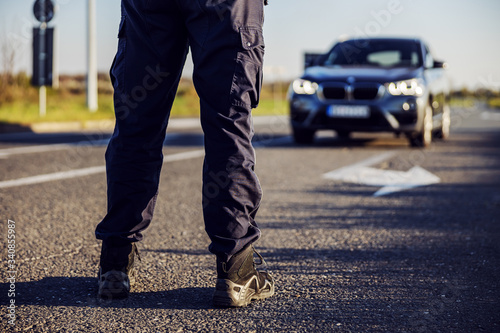 Police officer stops the car on the road.