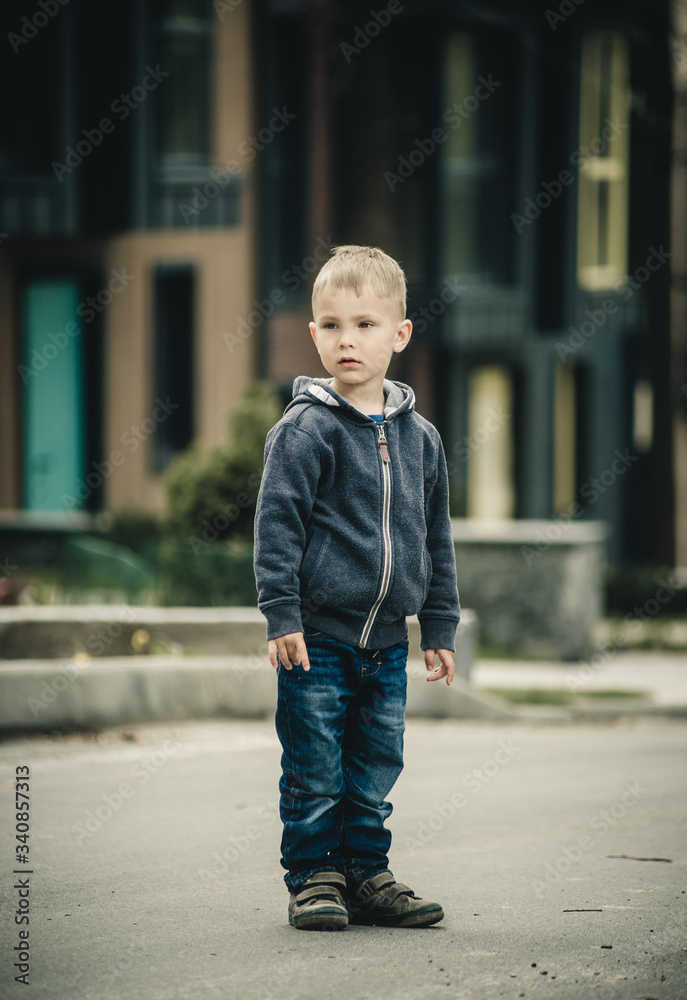 fashionable little boy near a cottage on the street