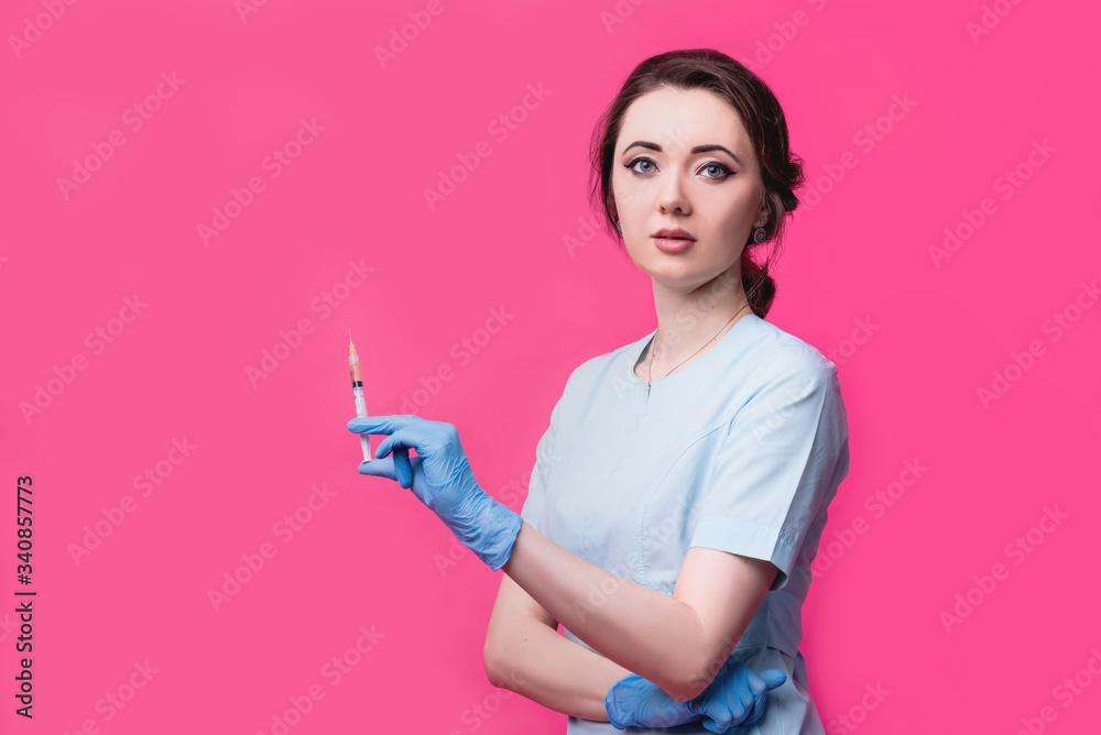 Woman cosmetologist doctor with a syringe in hands on a pink background in the studio. The concept of cosmetology, medicine and beauty Woman cosmetologist doctor with a syringe in hands on a pink background in the studio. The concept of cosmetology, medicine and beauty
