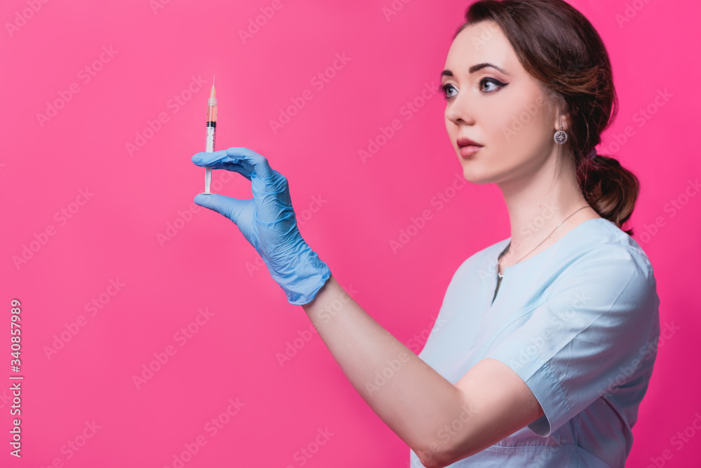 Woman cosmetologist doctor with a syringe in hands on a pink background in the studio. The concept of cosmetology, medicine and beauty Woman cosmetologist doctor with a syringe in hands on a pink background in the studio. The concept of cosmetology, medicine and beauty